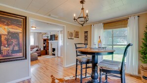A dining area with a round table, black chairs, a chandelier, and a cowhide rug. - Rusk Retreat w/ Fire Pit, Grill & Countryside View (Rusk)