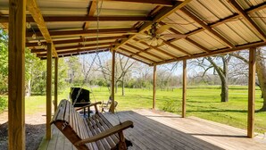 A wooden deck with a swing and a grill area, overlooking a grassy field. - Rusk Retreat w/ Fire Pit, Grill & Countryside View (Rusk)