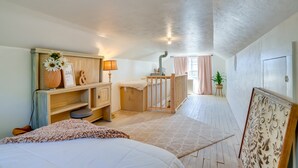 A bedroom with a bed, a wooden dresser, a nightstand, a lamp, a crib, and a window with curtains. - Rusk Retreat w/ Fire Pit, Grill & Countryside View (Rusk)