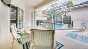 A covered patio area with a pool, outdoor seating, and a glass door leading to a poolside area.