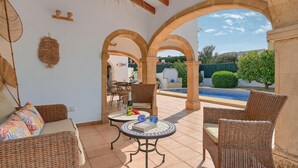 A patio area with wicker furniture, a table with decorative items, and a view of a swimming pool. - Wonderful and comfortable villa  with private pool in Javea, Costa Blanca, Spain for 6 persons (Javea)