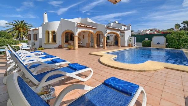 A poolside area with lounge chairs, a swimming pool, and a building with arched doorways. - Wonderful and comfortable villa  with private pool in Javea, Costa Blanca, Spain for 6 persons (Javea)