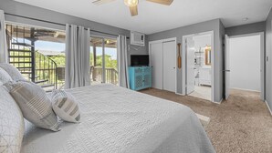 Ein Schlafzimmer mit einem großen Bett, einem Deckenventilator, einem Fernseher und Blick auf einen Balkon.
