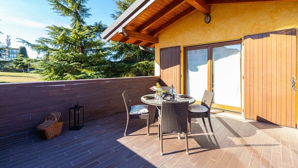 Eine Terrasse mit Tisch, Stühlen und einer Laterne, sowie ein Korbsessel.