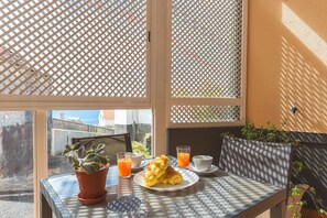 Una mesa con un vaso de jugo de naranja, un plato de croissants, una taza y una planta en maceta.