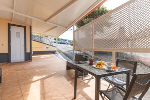 A covered outdoor seating area with a table set for breakfast, including croissants and orange juice. - Gomes House by Atlantic Holiday (Ponta do Sol)