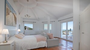 A bedroom with a bed, bedside tables, a chair, and a view of the outside. - Castillo de Troya - Denia, Costa Blanca (Denia)