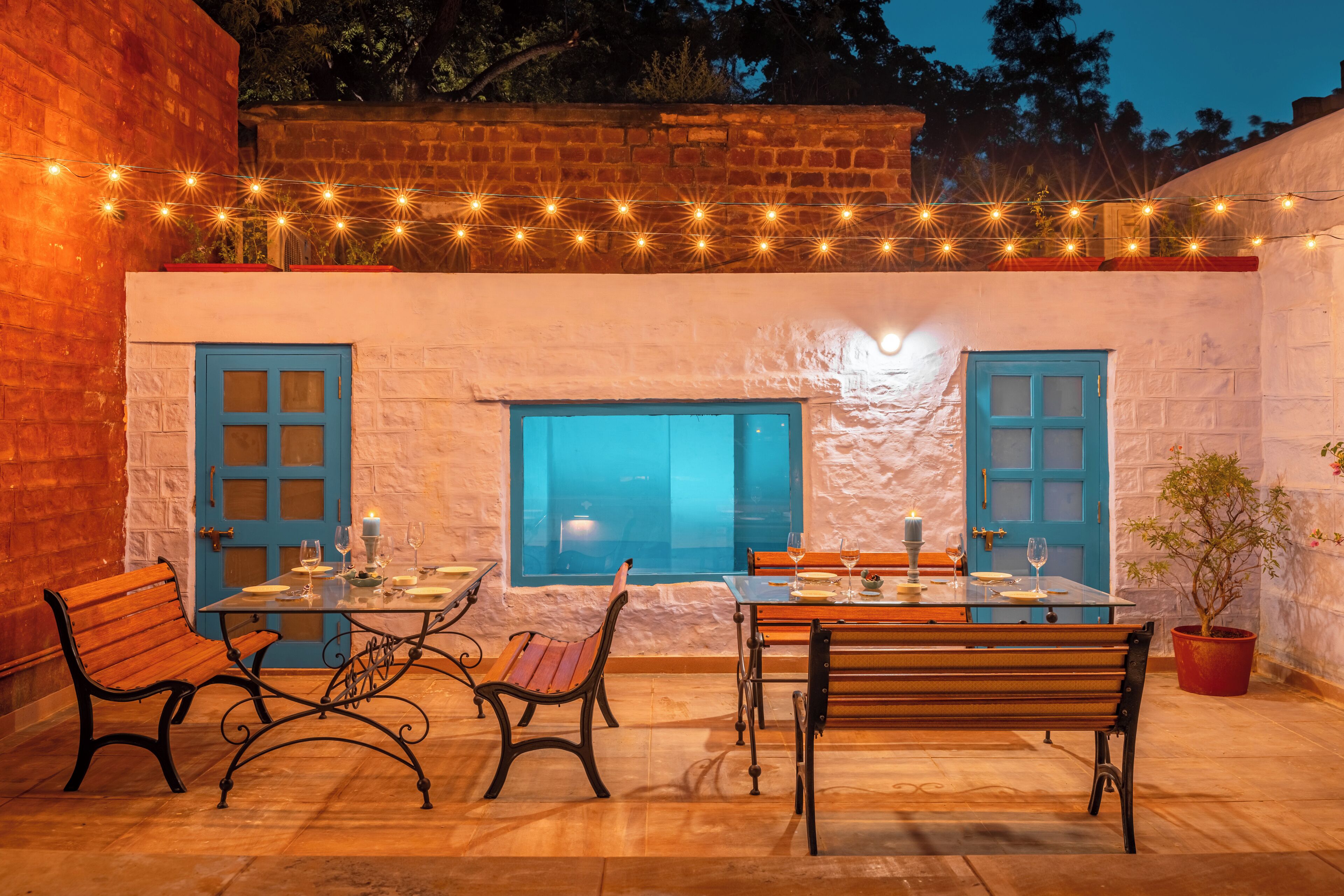 Eine Terrasse im Freien mit Esstisch, Bänken und Lichterketten.