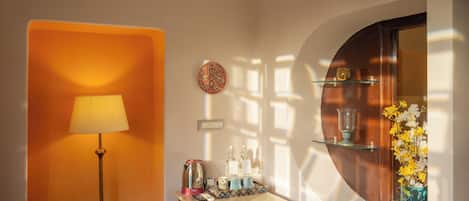 A well-lit room with a floor lamp, a small table with a tray of items, and a vase with flowers.
