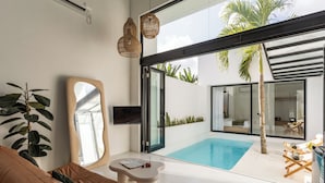 Una sala de estar moderna con piscina, un sofá, una mesa de centro y un espejo grande.