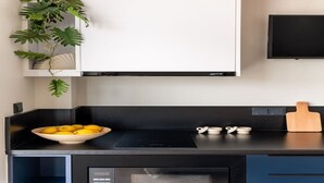 A modern kitchen with a black countertop, a built-in microwave, and a bowl of lemons. - Exceptional Living Loft 801 (Athina)