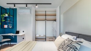 A modern bedroom with a bed, a desk, and a walk-in closet. - Exceptional Living Loft 704 (Athina)