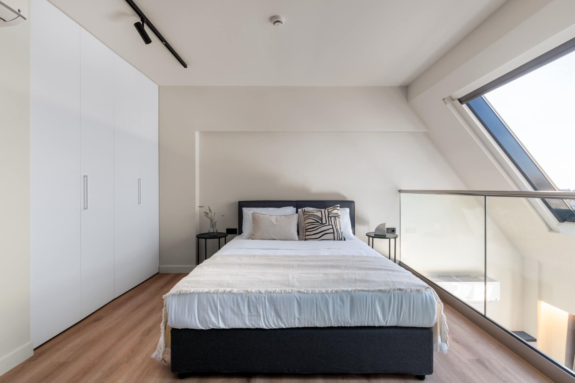 Un dormitorio moderno con una cama grande, un tragaluz y vistas a la ciudad.