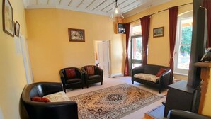 A living room with two black leather sofas, a patterned rug, a wooden ceiling, and a fireplace. - Tregonning Cottage Waipiata (Waipiata)