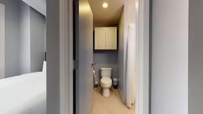 bathroom with a shower, toilet, and storage cabinet.