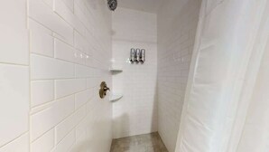 A narrow bathroom with white tiled walls and a shower area. - Downtown Crossing, Affordable Stay, Book Now! (Boston)