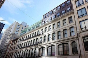 Un edificio de varios pisos con un estilo arquitectónico clásico, que presenta ventanas en arco y un balcón en el segundo piso.