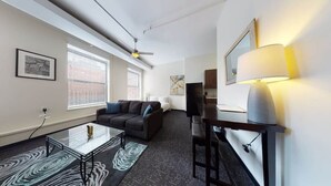 A modern living room with a sofa, a glass coffee table, a TV, and a lamp.