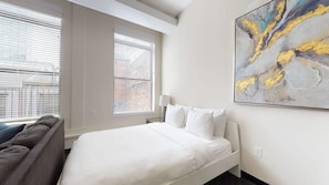 Quarto de hotel com cama, sofá e uma grande pintura abstrata na parede.