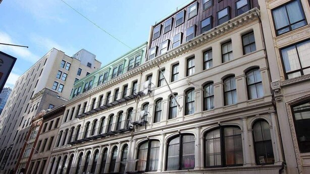 Un immeuble à plusieurs étages, de style architectural classique, caractérisé par des fenêtres en arc et un balcon.