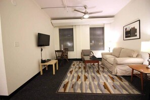 A living room with a ceiling fan, a television, a sofa, a coffee table, and a patterned rug. - Perfect One Bedroom Stay In Downtown Boston! (Boston)