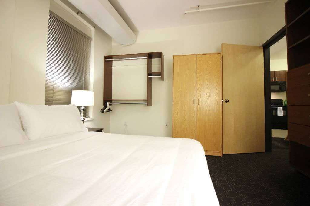 Ein Hotelzimmer mit einem Bett, einer Nachttischlampe, einem Holzschrank und einem Spiegel an der Wand.