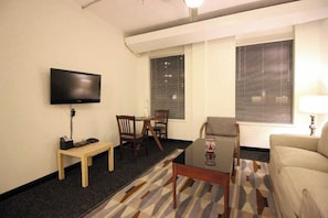 A small, well-lit room with a television, a dining table with chairs, a sofa, and a patterned rug. - Perfect One Bedroom Stay In Downtown Boston! (Boston)