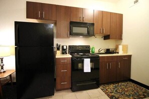 A compact kitchen with dark wooden cabinets, a black refrigerator, a microwave, and a stove. - Perfect One Bedroom Stay In Downtown Boston! (Boston)