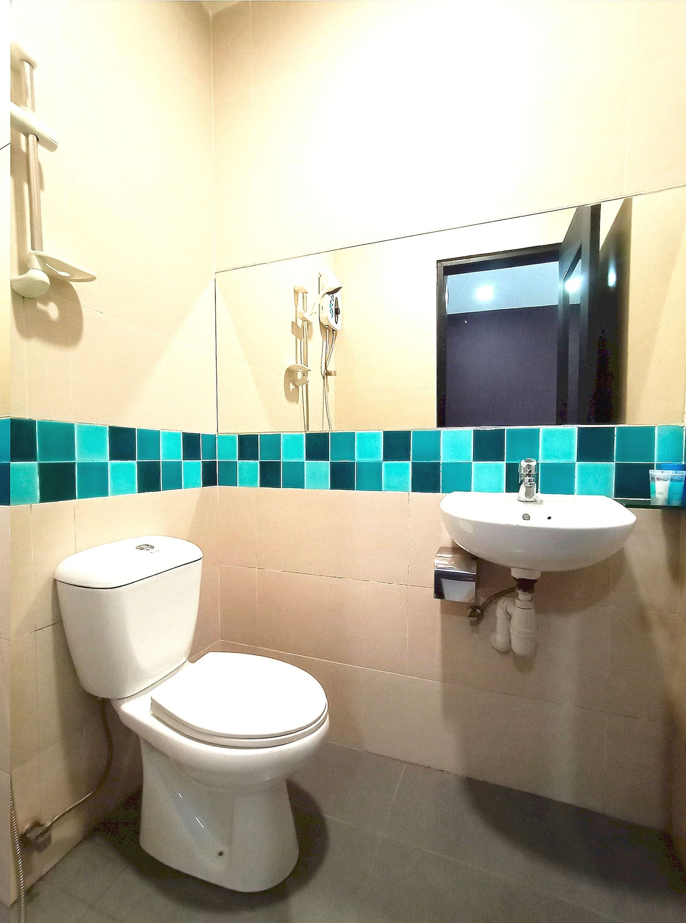 A bathroom with a toilet, a sink, and a mirror.