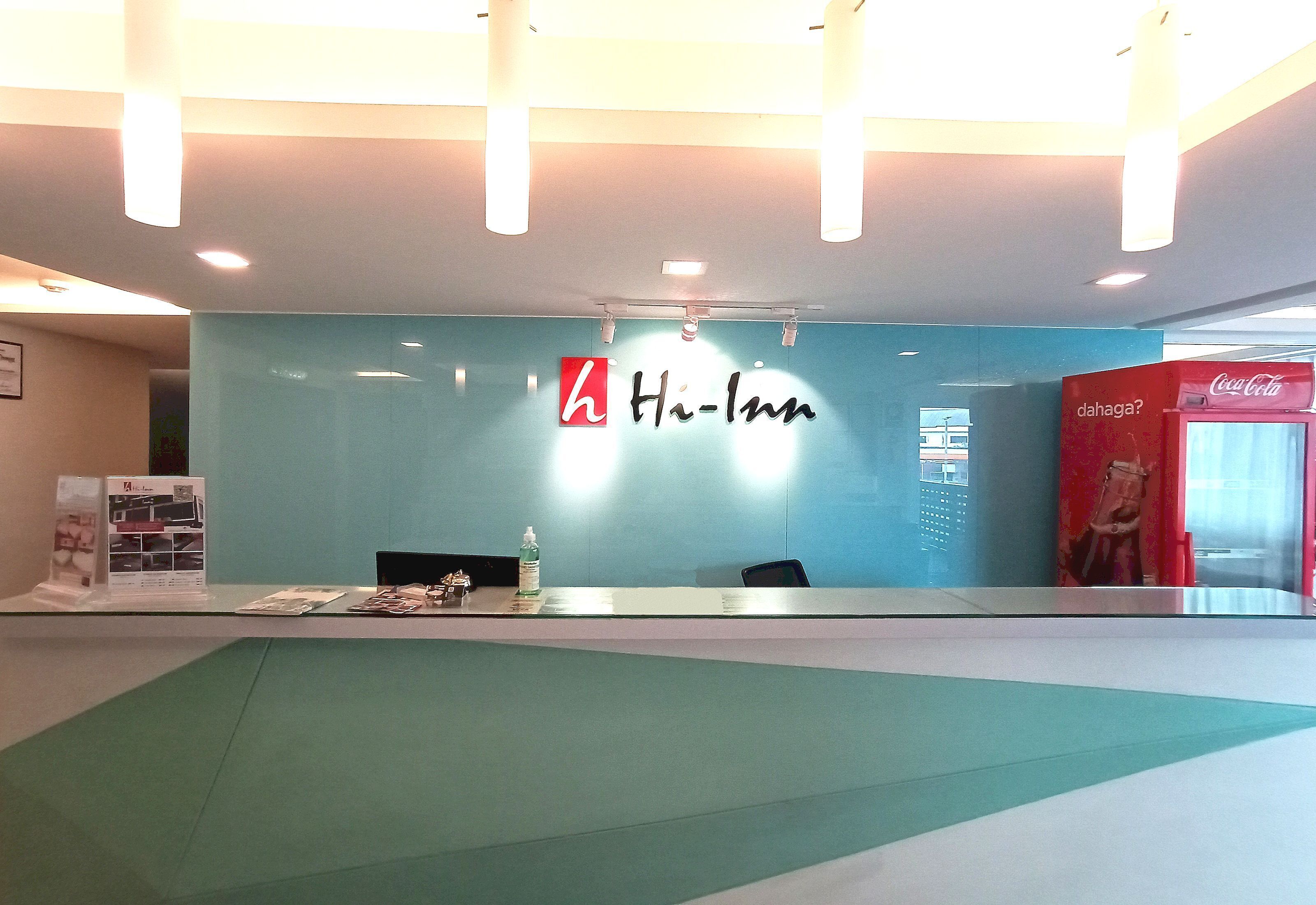 A reception area with a blue wall, a Coca-Cola vending machine, and a reception desk.
