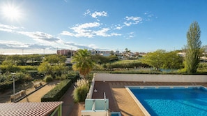 A rooftop swimming pool with a clear view of the surrounding landscape, including buildings and greenery.