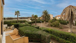 Une cour agrémentée de haies soigneusement taillées, de palmiers et offrant une vue sur la mer.