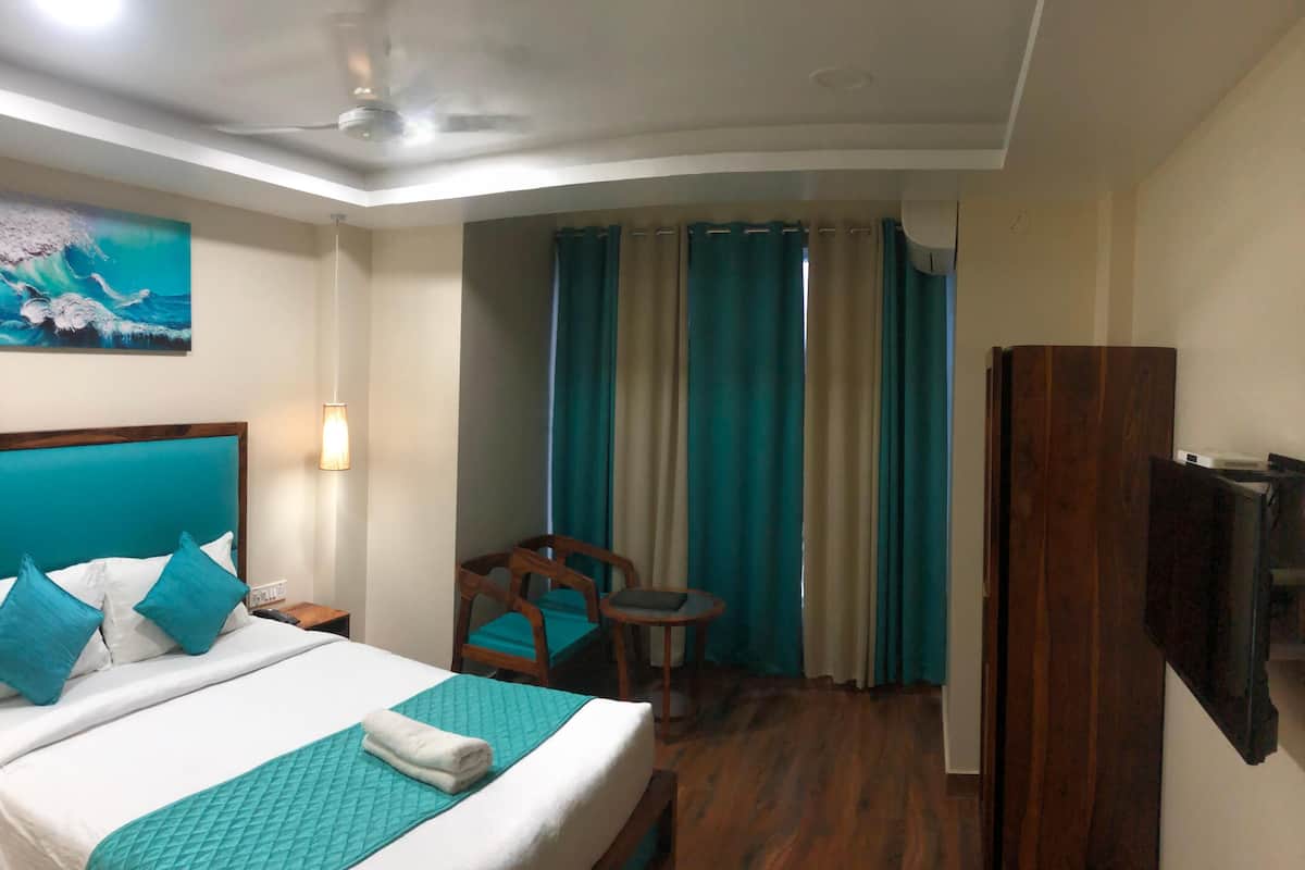 A hotel room with a bed, a desk, a chair, a TV, and a window with curtains.