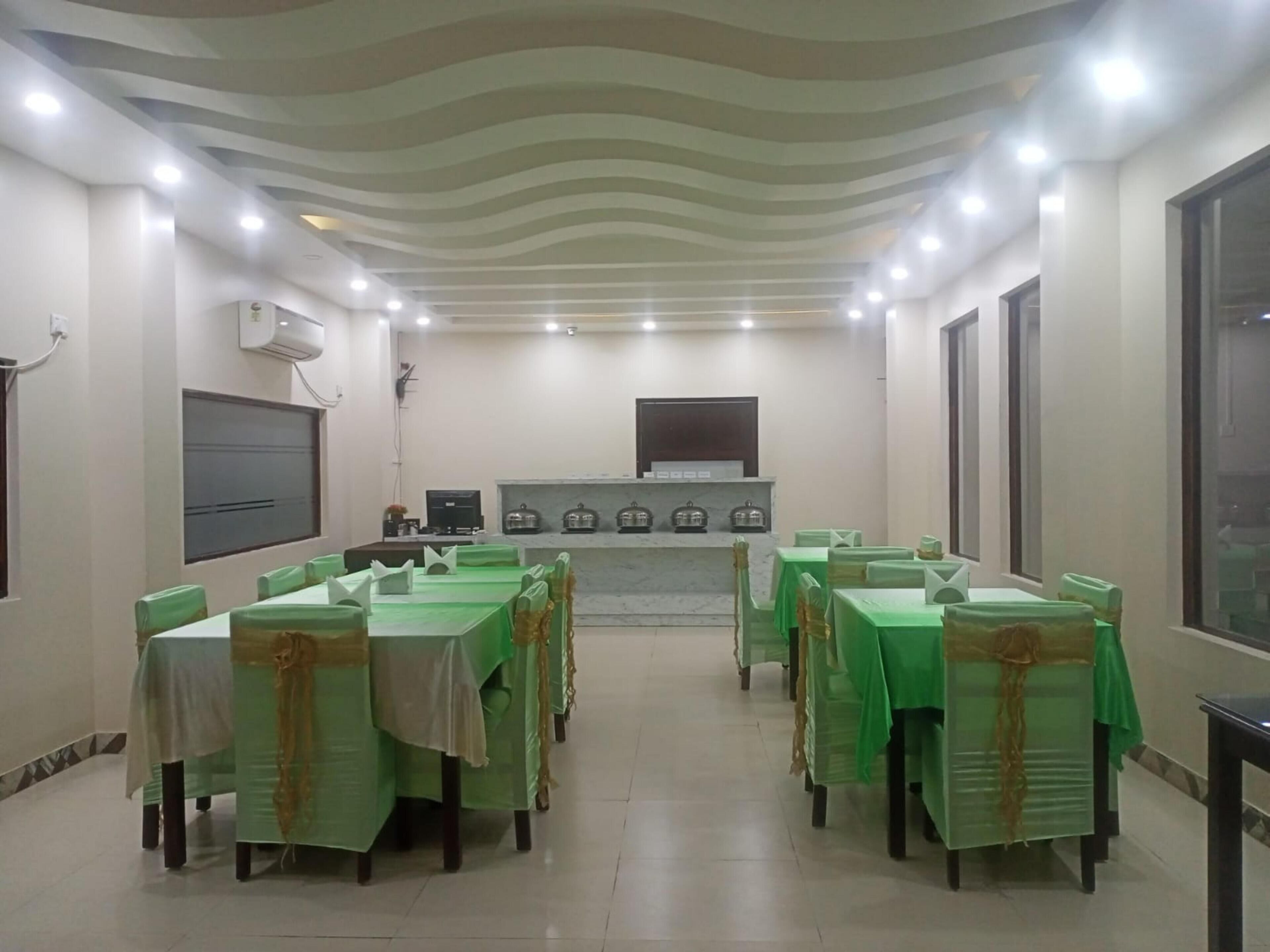 Un salón de conferencias con mesas y sillas cubiertas de verde, una chimenea de mármol e iluminación empotrada.