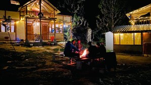 A rustic wooden building with a dining area and a fire pit. - Zevibes Cafe & Homestay (Bhuntar)