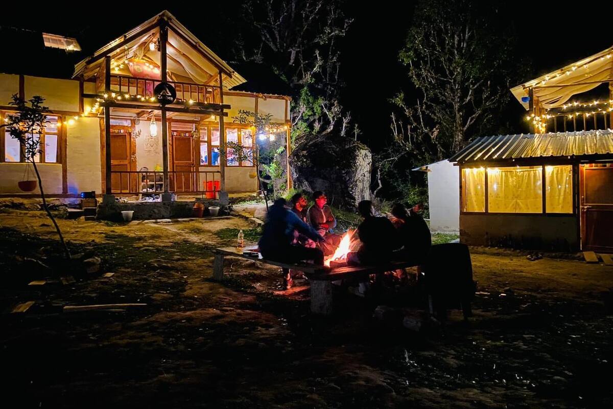 A rustic wooden building with a dining area and a fire pit.