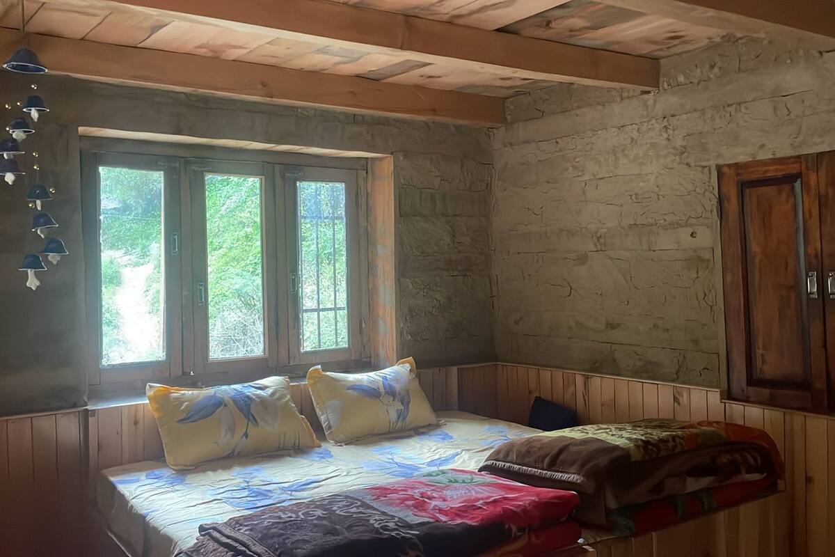 A rustic room with a bed, wooden walls, a window, and a wardrobe.