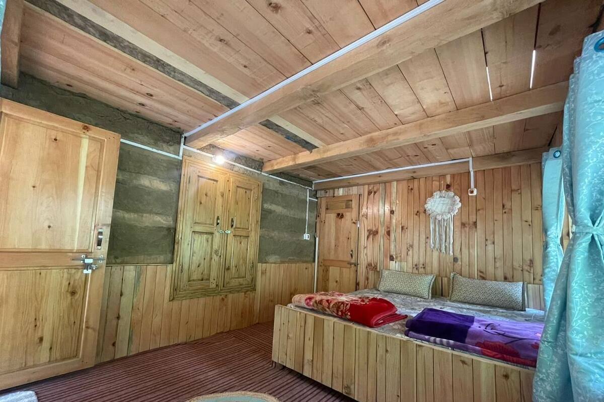A wooden-paneled room with a bed, a wardrobe, and a hanging light fixture.