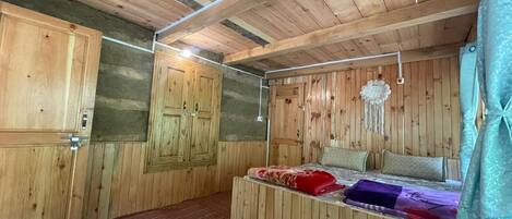 A wooden-paneled room with a bed, a wardrobe, and a hanging light fixture.
