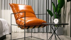 Una habitación moderna con un sillón de cuero, una mesita redonda y una planta en maceta.