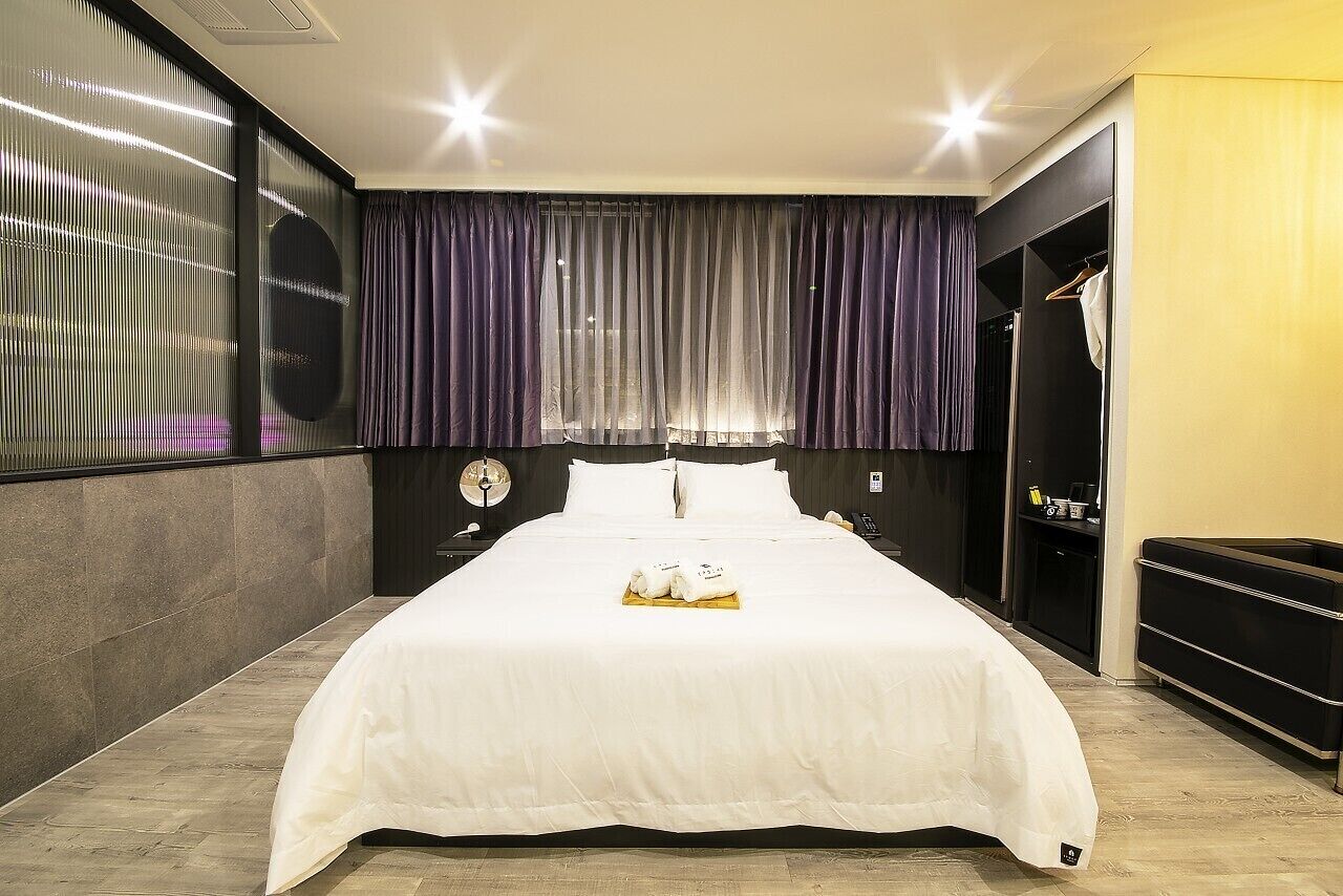 Une chambre d’hôtel avec un grand lit, une armoire et un miroir.