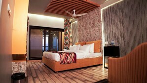 Una habitación de hotel moderna con una cama grande, un ventilador de techo, televisión y vistas al balcón.