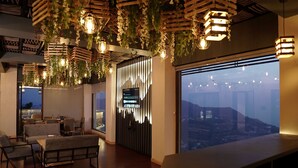 Un interior moderno con suelo de madera, una zona de bar, asientos y un amplio ventanal con vistas a la ciudad.