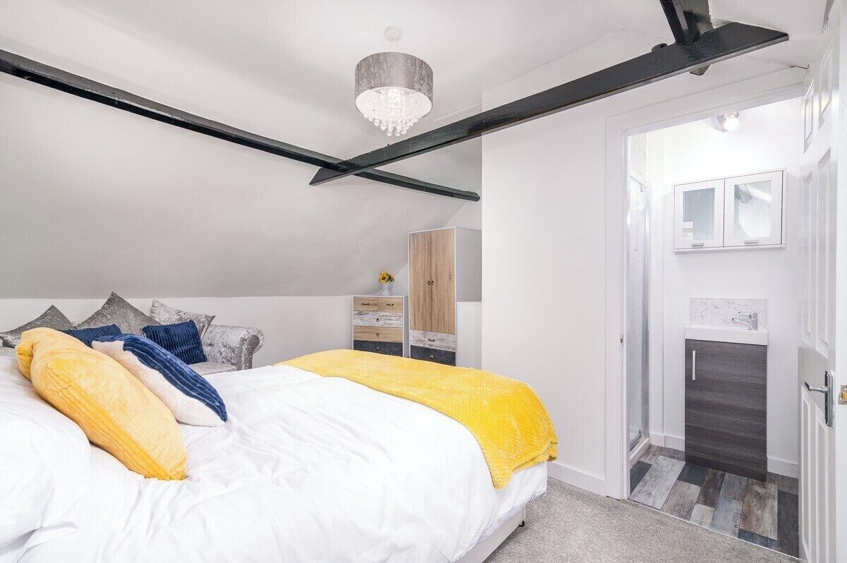 A bedroom with a bed, a wardrobe, a bathroom, and a chandelier.