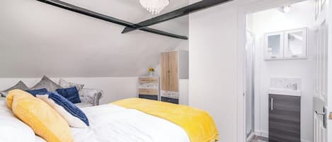 A bedroom with a bed, a wardrobe, a bathroom, and a chandelier.