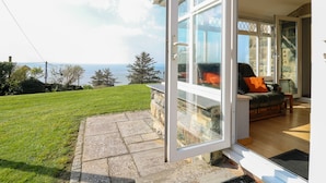A modern house with a glass door leading to a patio area with a view of the sea. - Mynydd ar Mor (Barmouth)