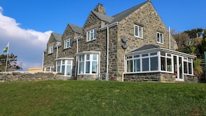 A stone house with multiple windows and a conservatory. - Mynydd ar Mor (Barmouth)