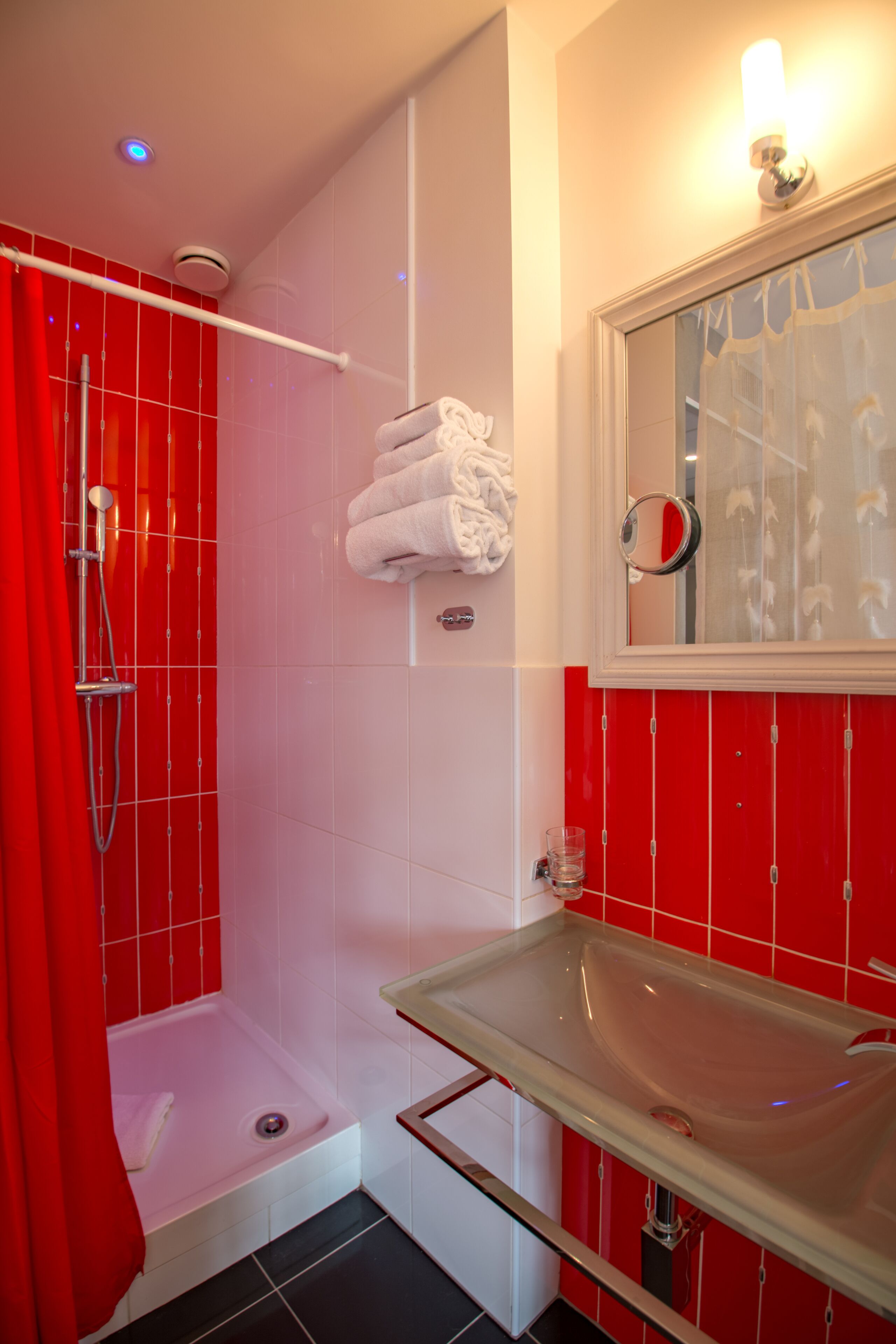 A bathroom with a red and white color scheme, including a shower, a sink, and a mirror.