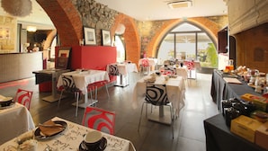 A restaurant with brick arches, white tables, and a view of greenery outside. - Hôtel Le Turenne (Beaulieu-sur-Dordogne)