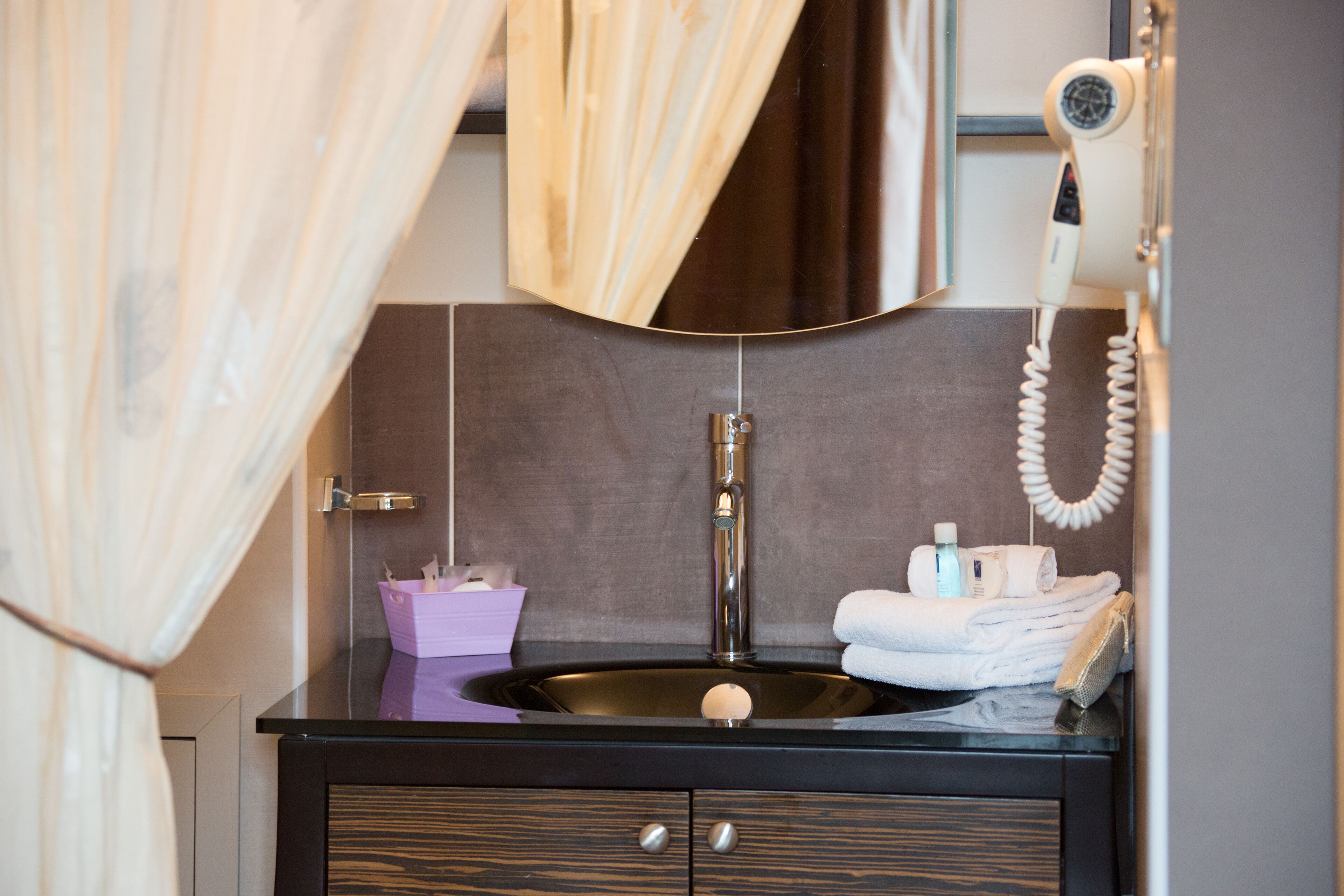A bathroom with a black vanity, a sink, a towel rack, and a hairdryer.